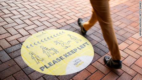 Seorang pejalan kaki berjalan melewati tanda jarak sosial pada 14 Agustus 2020 di Wellington, Selandia Baru.