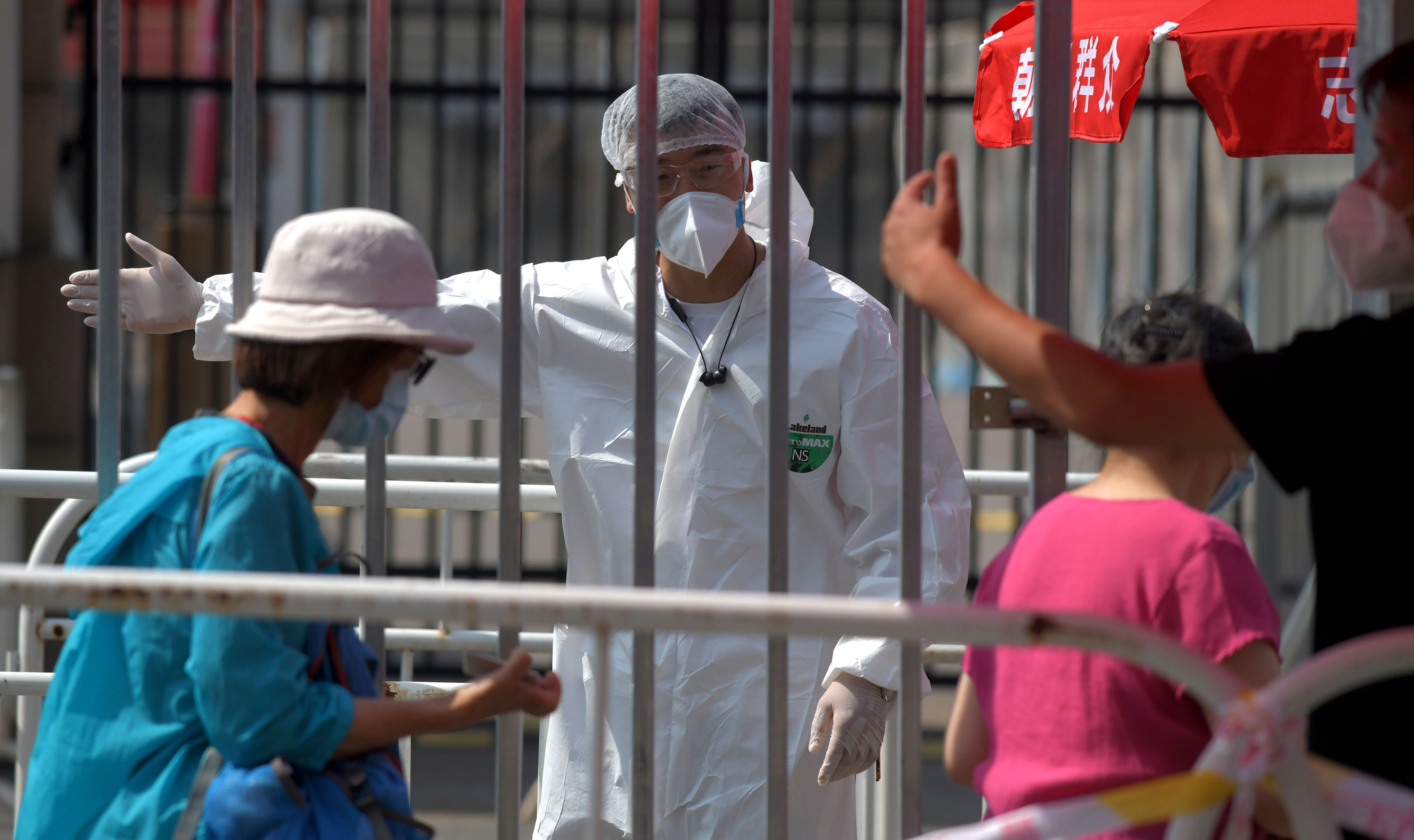 Pekerja mengarahkan orang di stasiun pengujian coronavirus pada 30 Juni di Beijing, Cina.