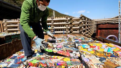 Seorang warga menumpuk lembaran kaleng aluminium yang dipadatkan di pusat limbah di Kamikatsu, Prefektur Tokushima.