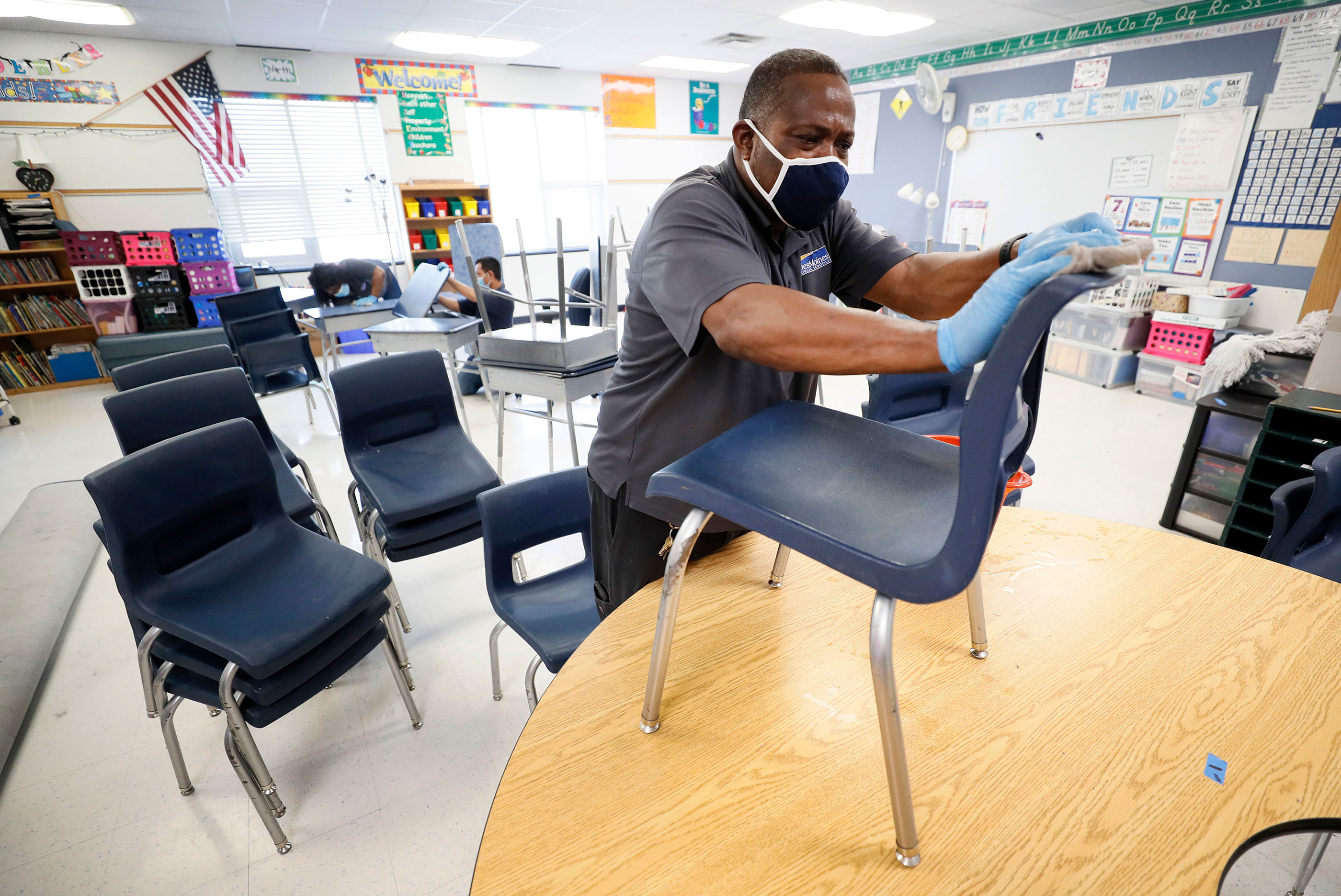 Kustodian Tracy Harris membersihkan kursi di ruang kelas di Sekolah Dasar Brubaker pada 8 Juli di Des Moines, Iowa.