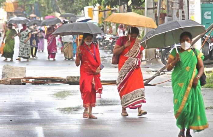 Bengaluru: Orang-orang melindungi diri mereka sendiri dengan menggunakan payung saat hujan di Bengaluru pada 20 Juli 2020.